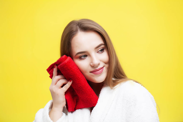 Młoda kobieta wycierająca twarz ręcznikiem na żółtym tle - Zdjęcie, obraz