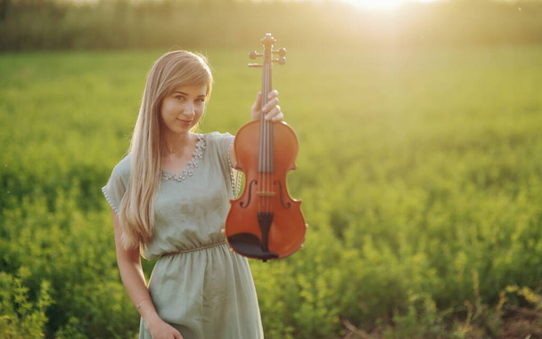Жінка-музикант скрипаль тримає скрипку в руках під час заходу сонця. Концепція навчання скрипки
 - Фото, зображення