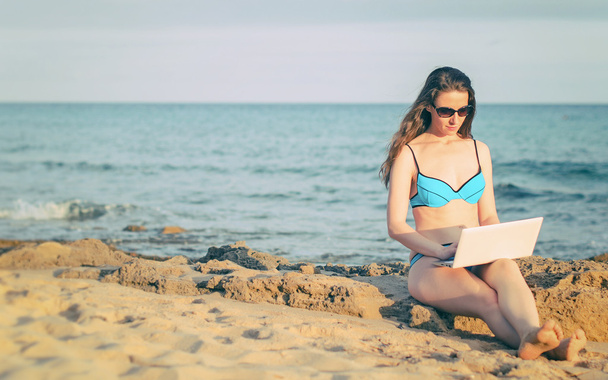 Woman with laptop working on the beach. Place for text. - Fotó, kép