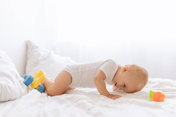 klein grappig baby jongen kruipen op het bed - Foto, afbeelding