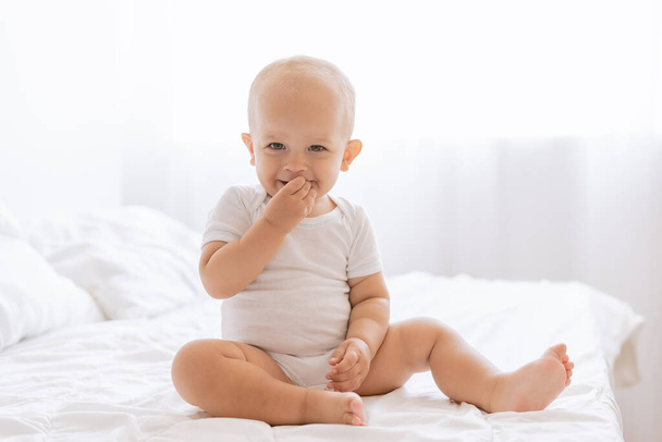 klein grappig jongetje op een wit bed - Foto, afbeelding