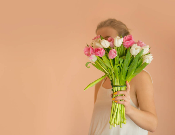 Portrét veselé mladé dívky v šatech s kyticí květin. Portrét krásné dívky v šatech drží tulipán kytice  - Fotografie, Obrázek