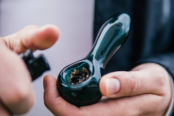Indica medical health. The pot leaves on buds. Cannabis nature bud. Marijuana weed bud and grinder. Smoking pipe in hand. Sativa THC CBD. - Photo, Image