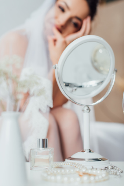 Szelektív fókusz tartozékok, tükör és üveg parfüm dohányzóasztalon közelében menyasszony otthon  - Fotó, kép