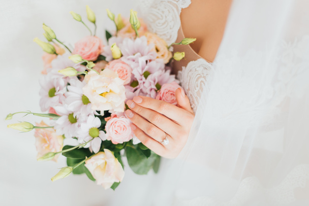 Cropped view of bride in wedding dress and veil holding floral bouquet  - Foto, imagen
