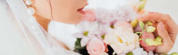 Panoramic shot of bride in pearl earring and veil touching bouquet  - Photo, Image