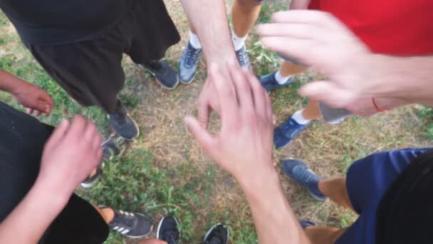 1つ1つを一つにまとめ若い選手のトップビューの手。親友のグループは円の中心に腕を置き、それらを上げる。友情とチームワークの概念。スローモ - 映像、動画