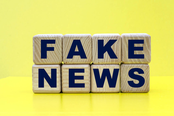 concetto parole fake news su cubi su sfondo giallo - Foto, immagini