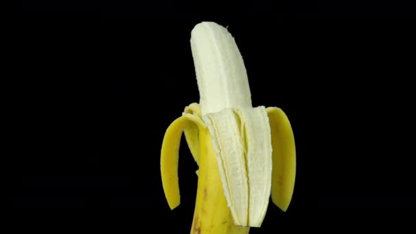 Animációs felvétel egy félig hámozott banánról, ami fekete háttér felé fordul - Felvétel, videó