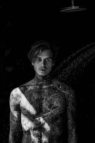 handsome young man in tattoos in the shower. lifestyle concept.  - Fotó, kép