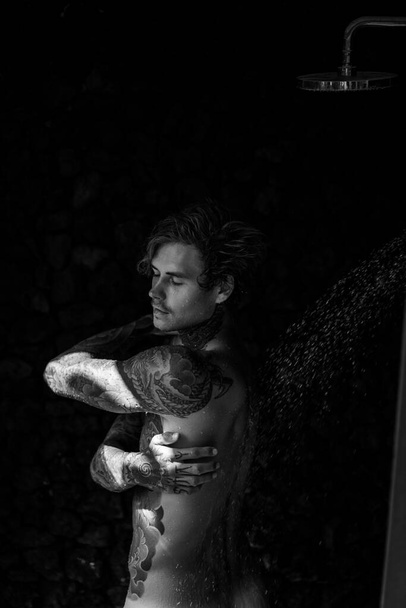 handsome young man in tattoos in the shower. lifestyle concept.  - Φωτογραφία, εικόνα