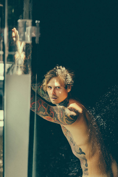 handsome young man in tattoos in the shower. lifestyle concept.  - Photo, image