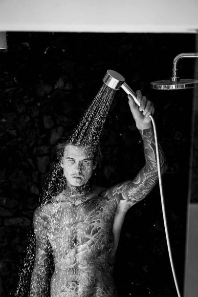 handsome young man in tattoos in the shower. lifestyle concept.  - Foto, Imagem
