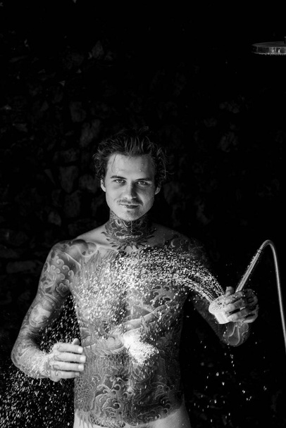 handsome young man in tattoos in the shower. lifestyle concept.  - Foto, Bild