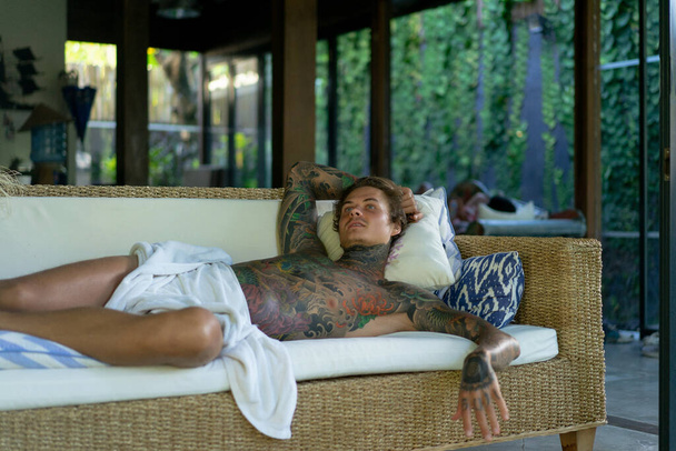 handsome young man in tattoos is resting in the living room - Foto, Imagem