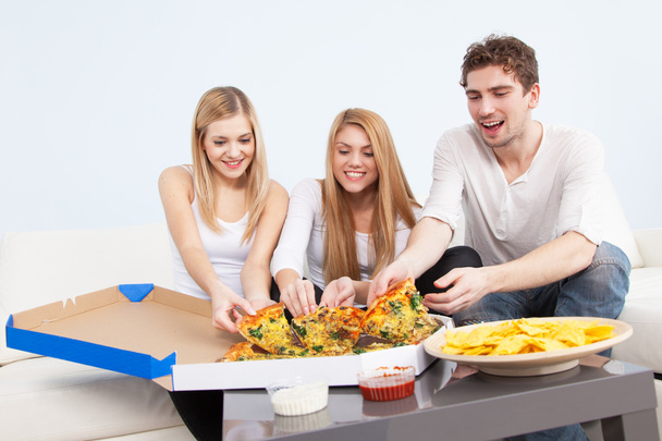 csoport fiatal otthon pizzát eszik - Fotó, kép