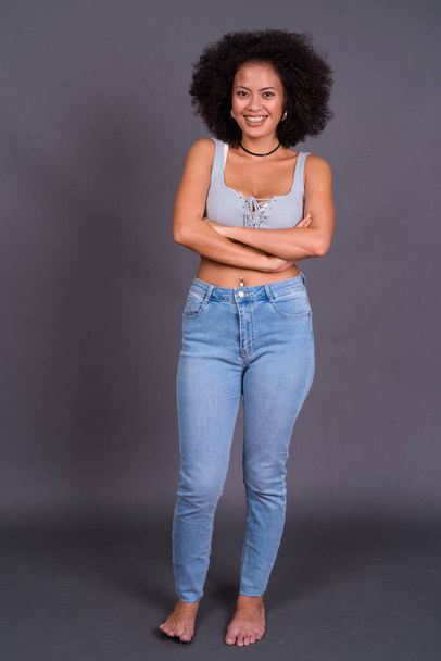Studyjne ujęcie młodej, wieloetnicznej Afroamerykanki z włosami afro na szarym tle - Zdjęcie, obraz