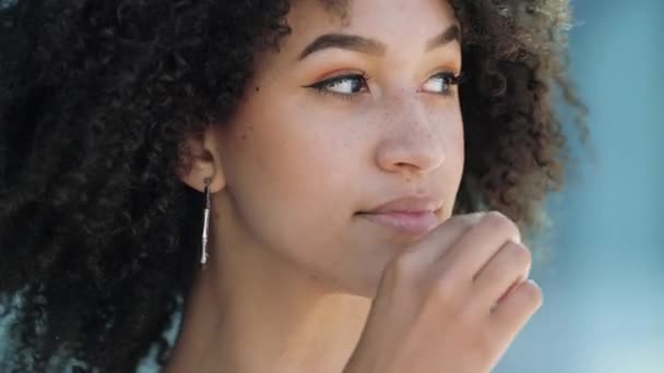 Egy közeli kép csinos afro-amerikai lányról, afro frizurával a szájában, záródó szájjal. Fiatal etnikai modell ravaszul mosolyog, utánozza a kulcsot, megígéri, hogy titokban tartja, titokzatos csend - Felvétel, videó