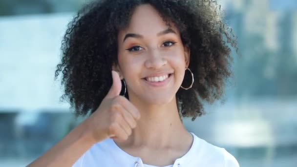Krásná afroamerická pozitivní dívka s afro zubatými úsměvy a ukazuje palec nahoru, gesto souhlasu. Etnická žena hledá s chválou, dobré recenze a pozitivní zpětnou vazbu, úspěch, souhlas a štěstí. - Záběry, video