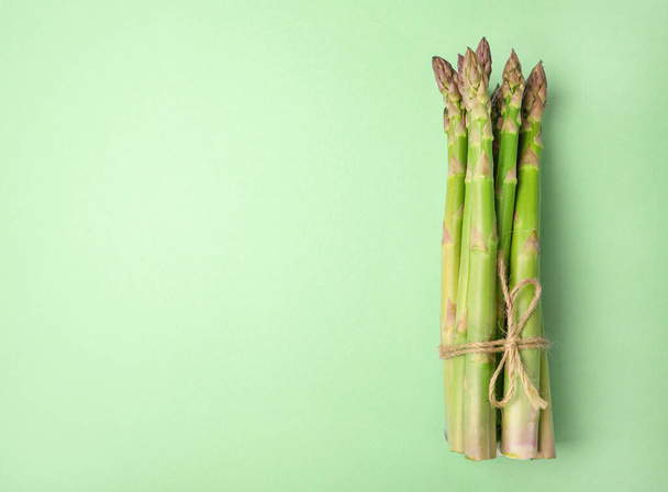 Fresh asparagus heap on light green background. Top view. Copy space. - Foto, afbeelding