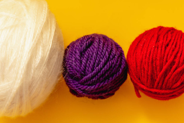on a yellow background are balls of woolen threads of red, blue and white color - Photo, Image