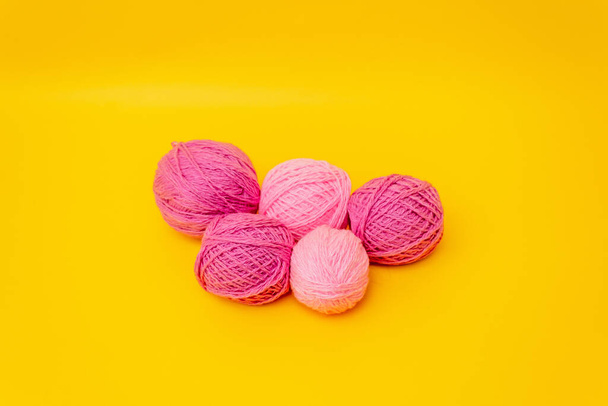 op een gele achtergrond is een stapel van wol draden in lila, roze kleuren - Foto, afbeelding