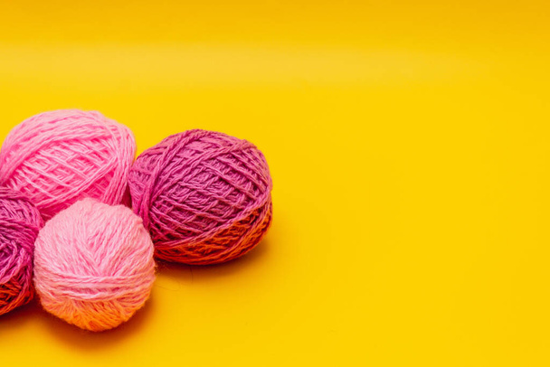 on a yellow background is a pile of wool threads in lilac, pink colors - Fotografie, Obrázek