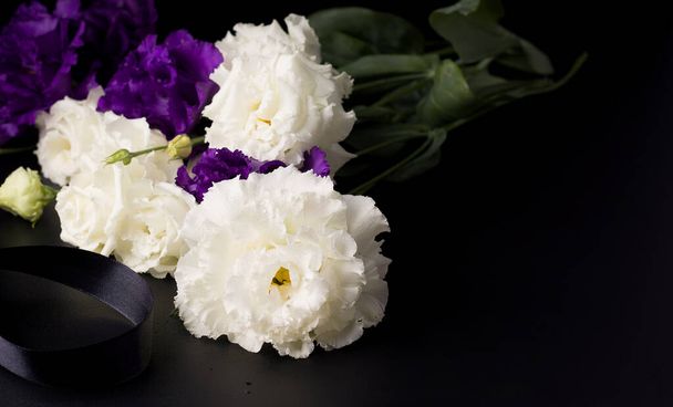 黒を背景に白と紫の葬儀花。. - 写真・画像