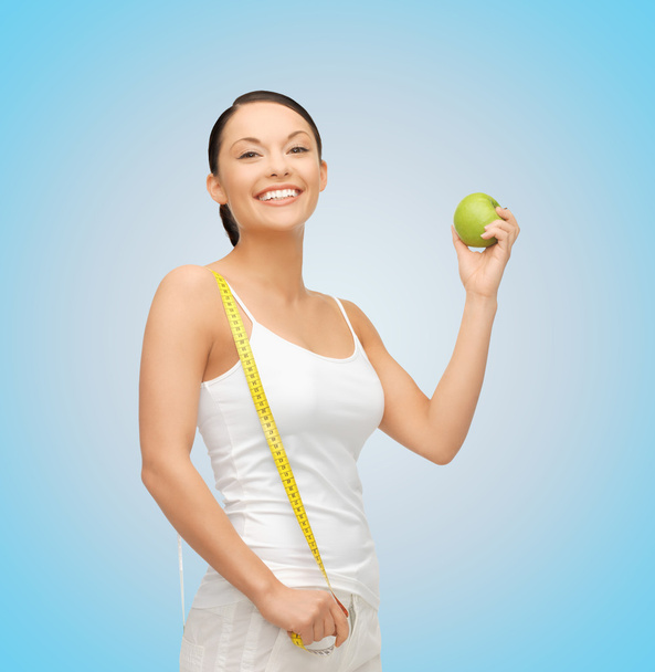 Sporty woman with apple and measuring tape - Valokuva, kuva
