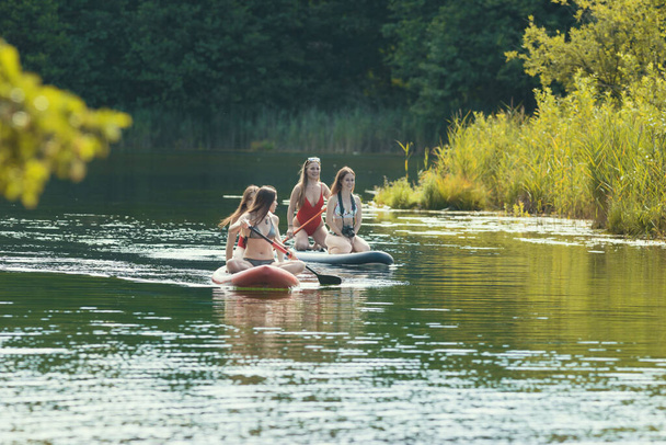 Four women sailing on the inflatable mattresses on river - Photo, Image
