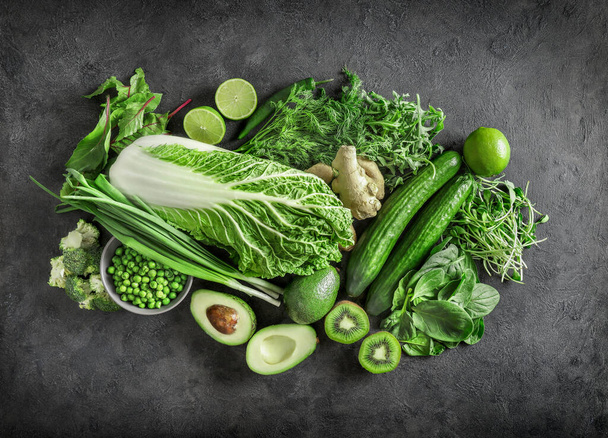 Top view of healthy organic food: green vegetables and herbs on dark background. Source of protein for vegetarians. - Photo, Image