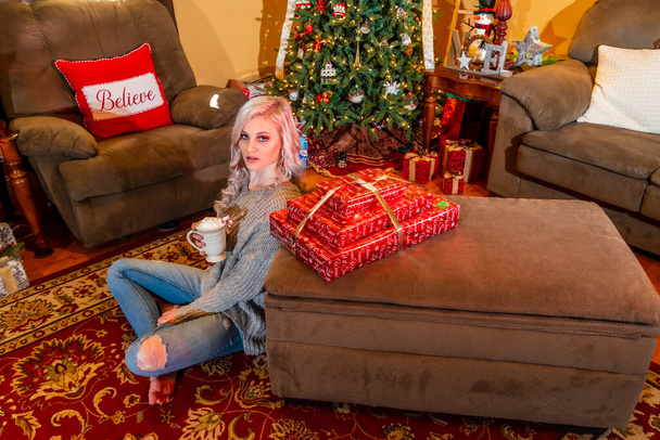 Una hermosa modelo rubia disfruta de la temporada navideña en casa con un árbol de Navidad y regalos - Foto, Imagen