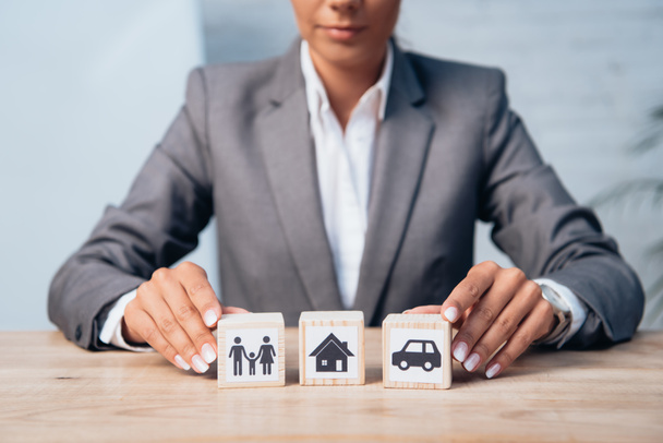 cropped view of woman touching wooden cubes with family, car and house  - Photo, Image