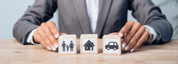 horizontal crop of woman touching wooden cubes with family, car and house  - Photo, Image