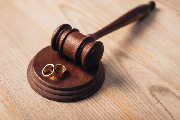 επιλεκτική εστίαση των χρυσών δακτυλίων στο ξύλινο σφυρί, έννοια του διαζυγίου  - Φωτογραφία, εικόνα