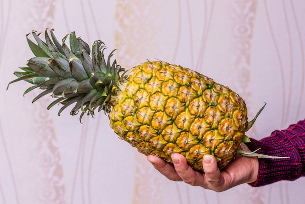 Ein Mann hält eine reife, schmackhafte Ananas in der Hand - Foto, Bild
