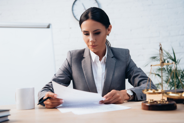 selective focus of brunette lawyer in formal wear looking at insurance documents in office - Фото, изображение