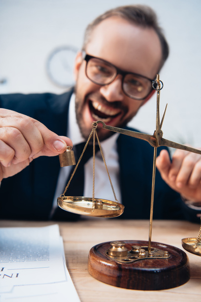 selective focus of excited lawyer in glasses holding miniature weights near scales - Photo, Image