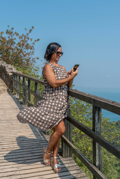 pretty woman on vacation uses smartphone to share content on social networks - Foto, Imagen