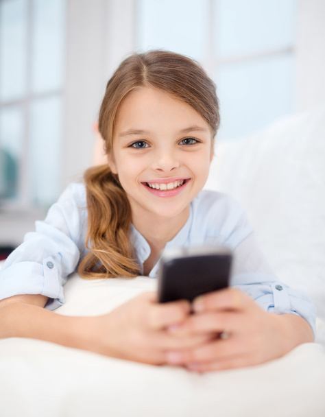 Smiling girl with smartphone at home - Φωτογραφία, εικόνα