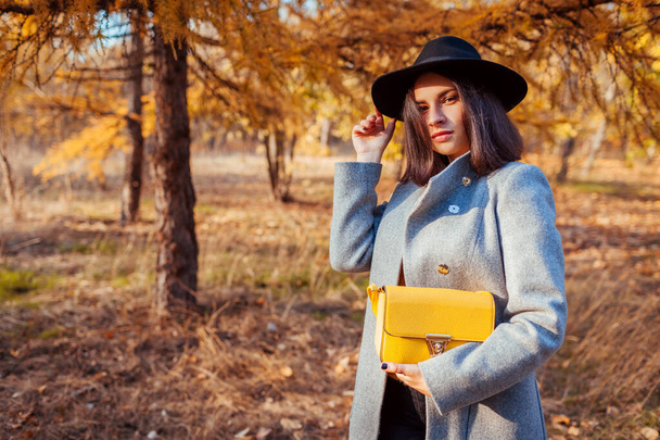 Moda de otoño. Mujer joven que usa un traje de suéter elegante y sostiene el bolso al aire libre. Ropa y accesorios - Foto, Imagen