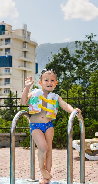 boldog kisfiú integetett a medence melletti kamera - Fotó, kép