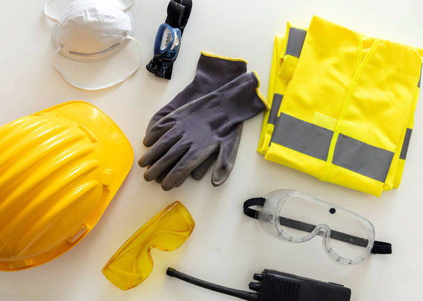 Work safety protection flat lay. Industrial protective gear reflective, fluorescent yellow color on white background, top view. Construction site health and safety equipment - Photo, Image