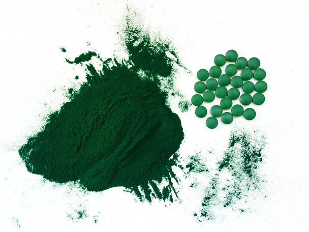 Groene hawaiiaanse spirulina in eetlepels pillen en poeder op lichtwitte achtergrond. Super food, gezonde levensstijl, gezonde supplementen concept - Foto, afbeelding