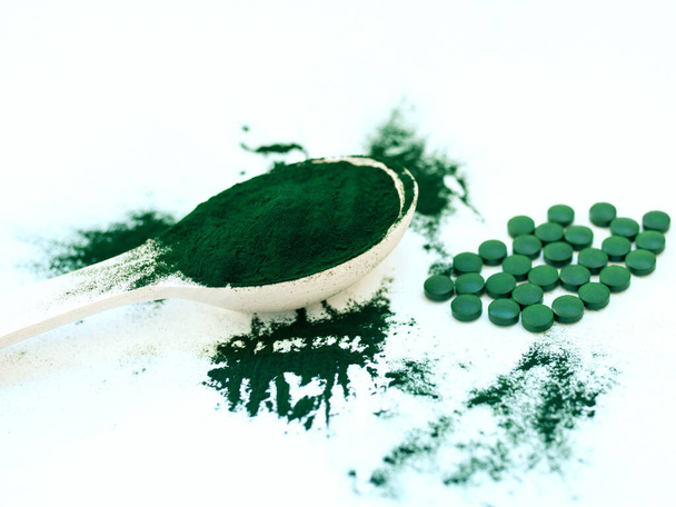 Zielona hawajska spirulina w tabletkach na łyżki stołowe i proszku na jasnobiałym tle. Super jedzenie, zdrowy styl życia, koncepcja zdrowych suplementów - Zdjęcie, obraz