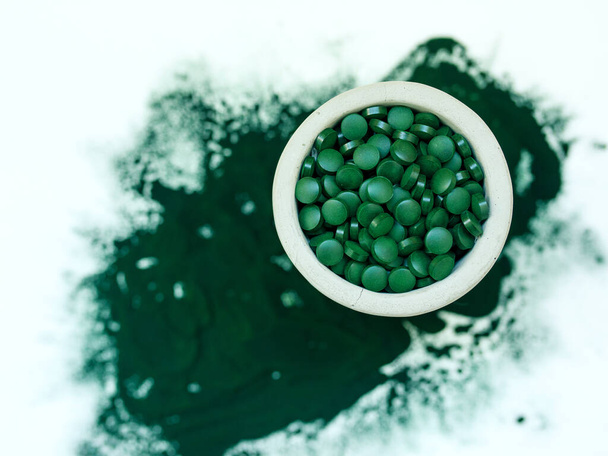 Grüne hawaiianische Spirulina in Esslöffeln Pillen und Puder auf hellweißem Hintergrund. Superfood, gesunde Lebensweise, gesundes Nahrungsergänzungsmittel-Konzept - Foto, Bild
