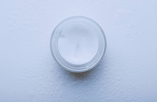 Vaso di crema su un tavolo bianco bagnato - Foto, immagini