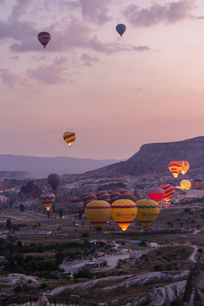 Μπαλόνια θερμού αέρα που πετούν περιοδεία πάνω από βουνά τοπίο κατά την ανατολή Καππαδοκία, Goreme Εθνικό Πάρκο - Φωτογραφία, εικόνα