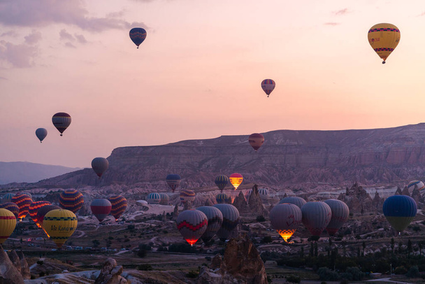 Sıcak hava balonları, güneş doğarken Cappadocia 'da, Goreme Ulusal Parkı' nda, dağların üzerinde uçuyor. - Fotoğraf, Görsel