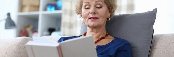 Grandmother sits at home and reads with enthusiasm - Foto, Imagem